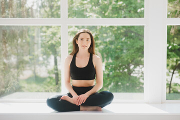 Fit woman making cobra pose on yoga mat, exercising in studio over panoramic window
