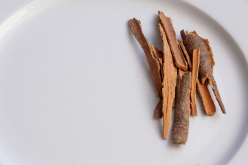 Natural cinnamon sticks on a white plate are isolated. Copy space.