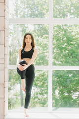 Fototapeta na wymiar Beautiful woman in grey sportswear, bra and leggings practicing yoga, standing in anjaneyasana pose, girl doing Horse rider exercise, working out at home or in yoga studio with white walls