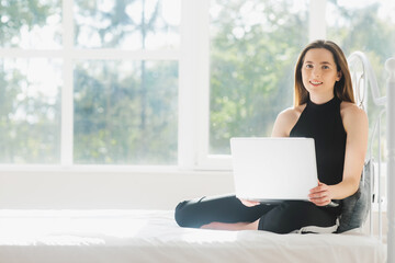 Image of young happy amazing pretty lady sitting on sofa indoors. Looking aside using laptop computer.