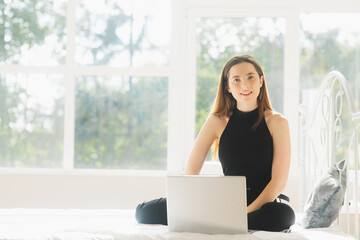Image of young happy amazing pretty lady sitting on sofa indoors. Looking aside using laptop computer.