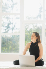 Image of young happy amazing pretty lady sitting on sofa indoors. Looking aside using laptop computer.