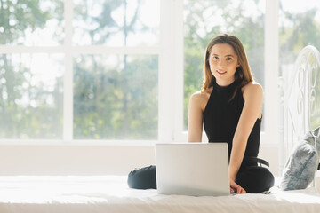 Image of young happy amazing pretty lady sitting on sofa indoors. Looking aside using laptop computer.