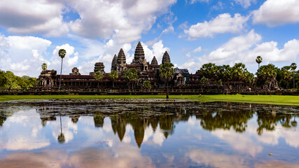 Fototapeta na wymiar It's Angkor Wat (Temple City) and its reflection in the lake, a Buddhist, temple complex in Cambodia and the largest religious monument in the world. View from the garden