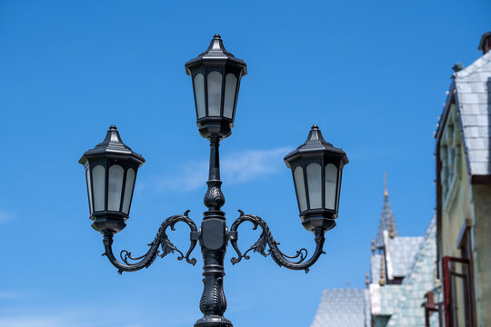 Street lamppost against the old buildings background. Classic victorian street lamps on an old fashioned iron lamp post set