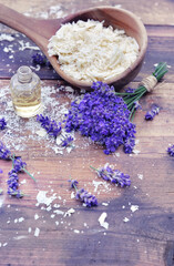 spoon full of flakes of soap with essential oil and bunch od lavender flowers on wooden background