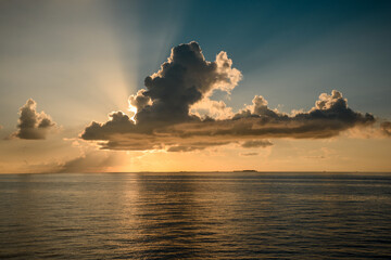 Colourful sunset in tropical islands with blue sky yellow clouds and sun rays in Indian Ocean in Maldives.