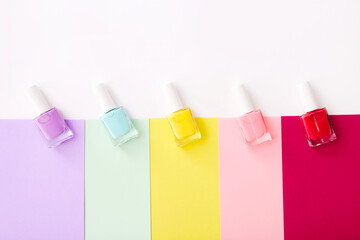 Group of nail polishes of different colors on colorful background. Top view