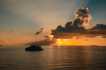 Colourful sunset in tropical islands with yacht, yellow clouds and sun rays