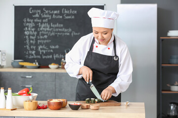Beautiful Asian chef cooking in kitchen