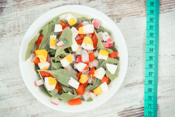 Centimeter and fresh salad in glass bowl, healthy nutrition, dieting and slimming concept