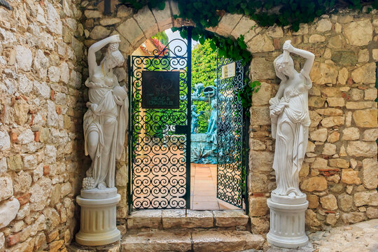 Eze, France - October 14, 2013: Ornate old wrought iron gate for the luxury hotel Chateau Eza and statues in the streets of a picturesque medieval city along the Mediterranean Sea