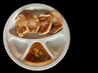 Puri and Potato Curry aalu sabji - an indian cuisine in round plate isolated on black dark background