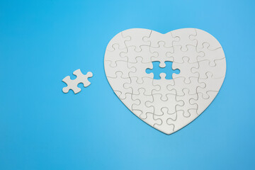 White heart shaped jigsaw puzzle on blue background with copy space. Business strategy teamwork and...