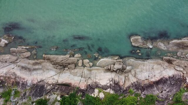 Aerial view of rock stone beach with turquoise water. Still camera.