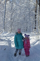 Fototapeta na wymiar Girls walk in the winter snow-covered forest 