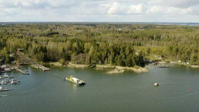 Aerial view panning away from a cable ferry in the archipelago of Porvoo, sunny, spring day, in Uusimaa, Finland -  pull back, drone shot,