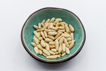 Pine nuts in ceramic bowl, isolated on white background
