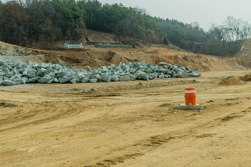 Quarried boulders stacked on ground at new construction site.