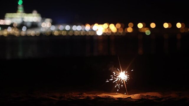 Burning sparkler in the sand on the beach at night