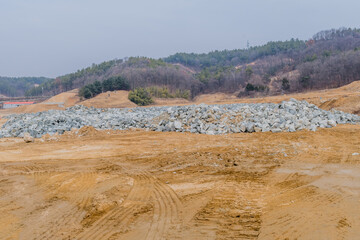 Quarried boulders stacked in open field at construction site
