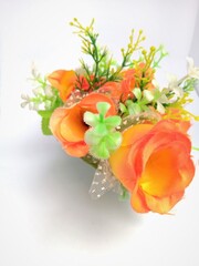 An orange colored rose plastic flower in a vase.
