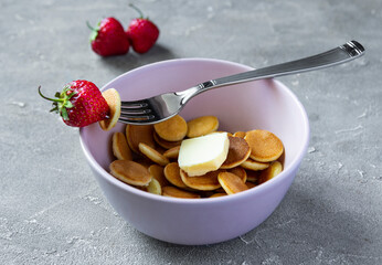 Pink Bowl with cereal tiny pancake with strawberries. Trendy food concept