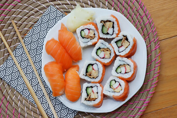 Sushi California rolls with ginger and chopsticks on a plate on wooden table. Delicoius Sushi food