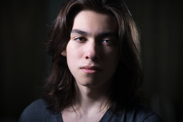 Portrait of young man with long hair in low key with Rembrandt lightning