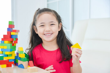 Pretty asian little girl playing colorful wood blocks at home. Child education concept.