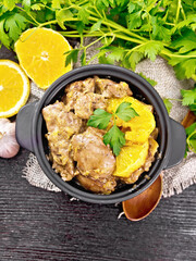 Liver with oranges in pan on dark board top