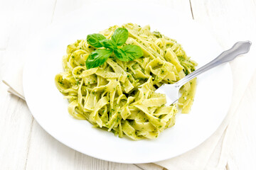 Pasta with pesto sauce in plate on wooden board