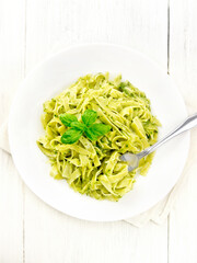 Pasta with pesto sauce in plate on light board top