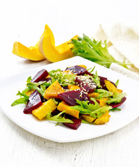 Salad of pumpkin and beetroot in plate on light wooden board