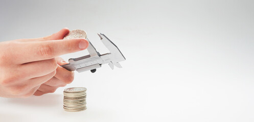 finance. hands holding calipers and silver coins on a light background