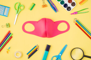 Top above overhead view photo of pink mask and colorful stationery isolated on yellow background