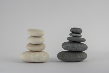 Two simplicity stones cairn isolated on white background, group of four and five black and white pebbles in tower