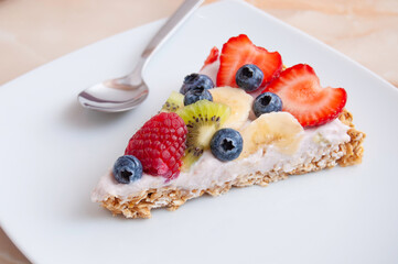 Slice of fruit cake on a white square plate, wood table