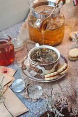 Cozy morning at home - old book and romantic letters to read, cup of delicious herbal tea with ginger and a jar of forest honey