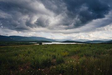 Fototapeta premium A lake in the valley among the mountains before it rains.