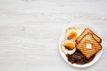 Homemade Healthy Sunnyside Eggs Breakfast on a white plate on a white wooden background, top view. Flat lay, overhead, from above. Space for text.