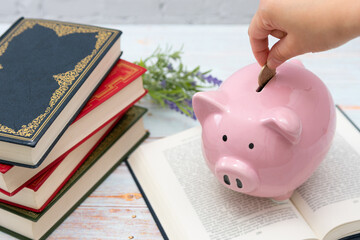 積み上げられた書籍とピンクの豚の貯金箱