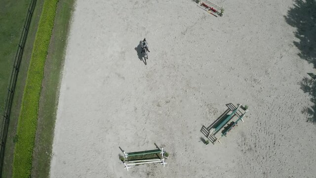 Pferd springt &uuml;ber Hindernis. Drohne verfolgt jungen Reiter. Sandplatz Parkour. Sprung
