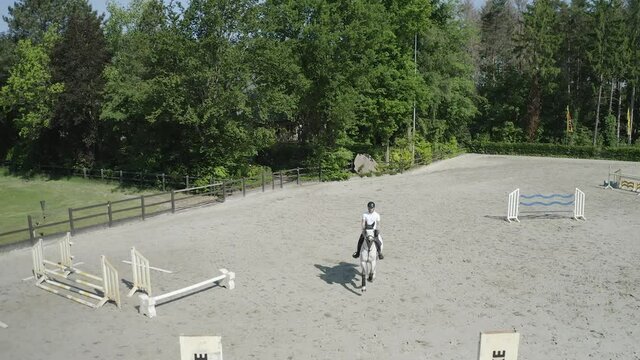 Pferd springt &uuml;ber Hindernis. Drohne verfolgt jungen Reiter. Sandplatz Parkour. Sprung