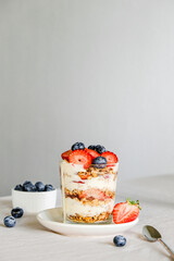 Homemade granola with berries and yogurt in a glass. Healthy eating Granola sprinkled on a white plate with fruit.
