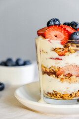 Homemade granola with berries and yogurt in a glass. Healthy eating Granola sprinkled on a white plate with fruit.