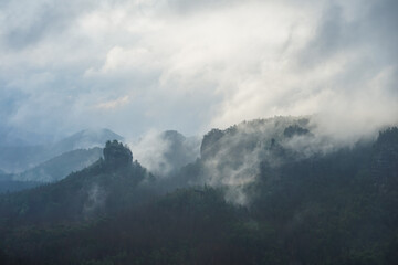 Dramatic foggy landscape with clouds in the morning in Saxon Switzerland, Germany