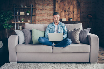 Photo of handsome homey guy relaxing sitting comfy couch legs crossed browsing notebook freelancer...
