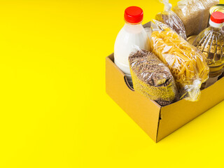 Food staples delivery or donation box concept on yellow background