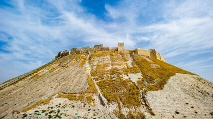 It's Citadel of Aleppo, a large medieval fortified palace in the centre of the old city of Aleppo, northern Syria. One of the oldest and largest castles in the world.